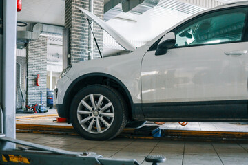 Aufkleber - White car with an open hood in an auto repair shop. Vehicle on a car lift for maintenance and inspection in a professional garage
