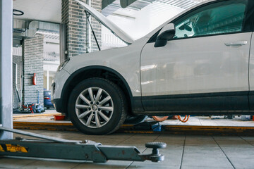 Aufkleber - White car with an open hood in an auto repair shop. Vehicle on a car lift for maintenance and inspection in a professional garage