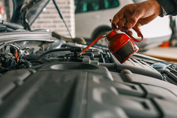Aufkleber - Mechanic using a red oil can to lubricate a vehicle's engine components during routine maintenance in a workshop