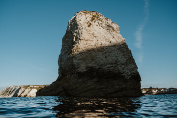 A large rock sits in the water, with the sky above it