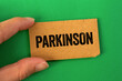 © Emre Akkoyun - Parkinson message written on cardboard paper on green background. Conceptual parkinson symbol. Copy space.