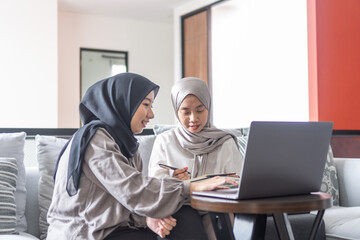 two moslem young women girl read laptop learn write book together living room home