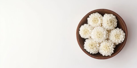 Aufkleber - In a white background featuring ample blank space, you can find dried white chrysanthemums arranged in a wooden bowl, creating a serene and minimalist display.