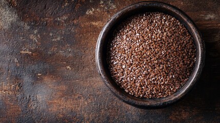 Aufkleber - A flatlay of whole fresh brown flaxseeds displayed in an antique iron bowl on a rustic brown wooden surface, showcasing the natural textures and colors of brown flaxseeds in an inviting composition.