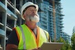 © Natawut - Construction worker evaluating project progress at urban site tablet in hand bright day