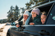 © DusanJelicic - Mother and daughters enjoying a winter road trip, gazing out the car window at a stunning snowy landscape, filled with joy and excitement during their family adventure