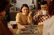 © AnnaStills - Medium close up of brunette woman enjoying her game turn while her boyfriend who sitting near her drinking tea