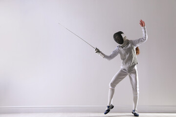 Fencer with epee practicing indoors, space for text