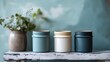 © Blackmint Studio - Experience the serenity of natural decor featuring slate blue jars adorned with vibrant greenery, all beautifully set against a soothing muted blue-gray backdrop in a tranquil, rustic environment