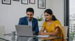 © Ployker - Indian business couple in traditional attire working together on laptop in modern office environment
