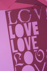 Wall Mural - machine-cut paper stencil with the word love repeated on pink