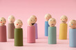 © Jakov Ilkoski - Image of different emotions on wooden peg dolls against pink background.