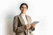 © Stock 4 You - Successful hispanic young manager business woman in suit, eyeglasses working on tablet standing confident. Isolated portrait of latin or eastern middle age female ceo leader businesswoman. Copy space