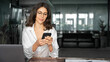 © Stock 4 You - Focused Latin Hispanic female businesswoman holding smartphone sitting at desk in office. Successful middle age business woman manager ceo using cell phone mobile pc for online working. Copy space