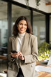 © Stock 4 You - Vertical portrait young successful business woman manager ceo using cell phone mobile looking at camera. Smiling Latin Hispanic female businesswoman holding smartphone in office for working videocall