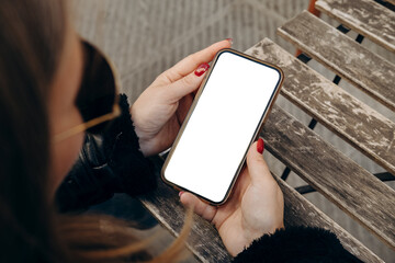 Mockup woman's hand holding using smart phone with white blank screen at coffee shop, mobile app design and advertising, online marketing