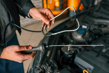 Fototapete - Mechanic using a diagnostic tool to check a car engine in a workshop, demonstrating vehicle maintenance and repair