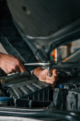 Aufkleber - Mechanic tightening a bolt on a car engine using a ratchet wrench in a professional workshop setting