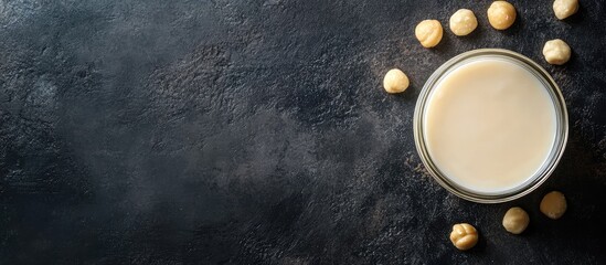 Aufkleber - Glass bowl with creamy liquid surrounded by hazelnuts on dark textured surface Copy Space