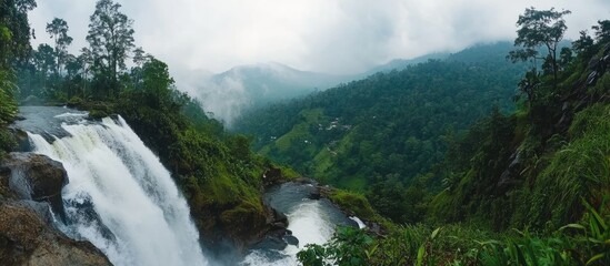 Poster - Lush green landscape with a cascading waterfall surrounded by mountains and misty clouds Copy Space