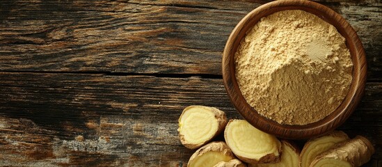 Poster - Ginger root slices beside a wooden bowl filled with ginger powder on a rustic wooden surface with Copy Space