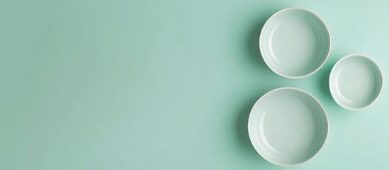 Poster - Three white ceramic plates on a mint green background with copy space for text or design elements.