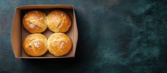 Poster - Freshly baked bread rolls in a cardboard box with a dark textured background and copy space for text