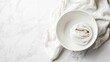 © CryptoCanvas - Minimalistic kitchen setting with white bowl and linen cloth on marble surface featuring ample copy space.