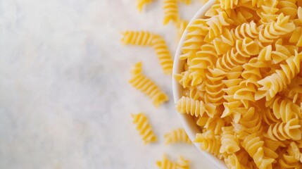 Leinwandbilder - Fusilli pasta in a white bowl with scattered pieces on a light textured background Copy Space