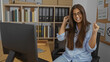 © Krakenimages.com - Young, brunette, woman, celebrating, success, in, bright, office, with, bookshelves, and, computer, indoor
