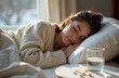 © Sanbora - A beautiful sleeping woman. A glass of water, pills, medicines are nearby. The concept of sleep deprivation, overwork. Treatment and prevention of insomnia, flu and colds. Healthcare and medicine.