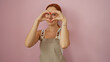 © Krakenimages.com - Young woman with red hair in an apron making a heart shape with her hands isolated over a pink background