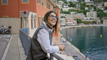 Wall Mural - Woman enjoying the scenic view of villefranche-sur-mer in france, smiling over the sea with colorful buildings and peaceful streets in the background.