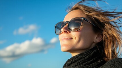 Aufkleber - Young woman wearing sunglasses and a black scarf enjoying the sun and clouds on a summer day, representing the concepts of travel, tourism, and holiday relaxation