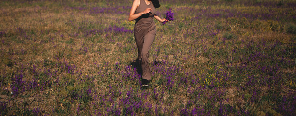 Wall Mural - girl with a bouquet of purple flowers in the sunset