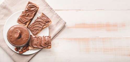 Canvas Print - Plate with bread and chocolate paste on light wooden background with space for text, top view