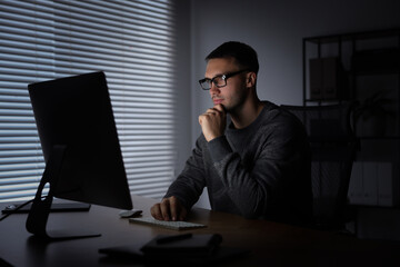 Programmer working on computer indoors at night