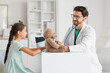 © Pixel-Shot - Male pediatrician with stethoscope listening to toy bear and cute girl in clinic