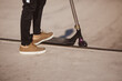 © Buyanskyy Production - Close-up of a scooter rider's legs wearing casual sneakers, standing at the edge of a skatepark ramp. Ideal for urban sports, youth culture, and active lifestyle concepts.