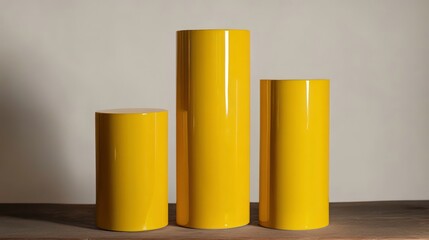 Aufkleber - Three yellow cylindrical pedestals of varying heights on a wooden surface against a neutral background.