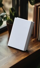 Poster - Blank Hardback Book on Wooden Desktop Surrounded by Plants and Books : Generative AI