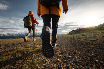 two young active female hikers tourists girls walks in sunset mountains. close up photo of woman leg