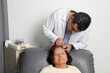 © Arlette - Elderly Latin woman undergoes EEG electroencephalogram to detect dementia or Alzheimer's disease in office with dark-skinned specialist doctor
