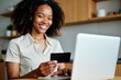 © SimpleDesignStudio - Cheerful Young Woman Shopping Online with Credit Card in Modern Kitchen, Embracing E-commerce Convenience and Digital Payment Solutions