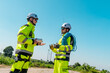 © Hip.hub - Workers in reflective gear engage in safety briefing near wind turbines under bright blue sky