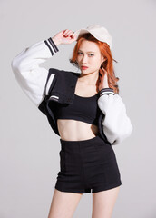 Wall Mural - Fashion portrait of asian beautiful sexy cheerful confident young woman with long orange hair model wearing fashionable black outfit and cap standing pose looking camera on white background in studio.