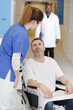 © auremar - beautiful young nurse helping a patient on his wheelchair