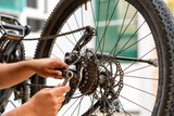 A young man repairing a bicycle using a combination wrench to repair a bicycle transmission and brake system.