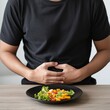 © Warinlada - Man sitting at table enjoying meal with plate of food and fork in indoor dining setting