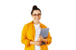 © Kateryna - Friendly caucasian or arabian woman in a yellow shirt with glasses, manager or teacher, holding a closed laptop, standing against a white isolated background, looks at camera, smiling confidently